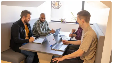 CloudM implementation services team huddle in a meeting nook